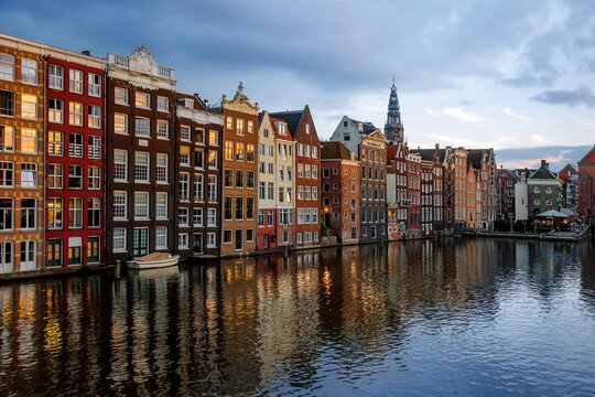 View across the Damrak canal of the Dancing Houses (Gingerbread houses) and the Oudekerksplein Tower at dusk, Amsterdam, Netherlands