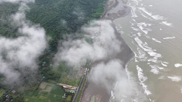 Aerial drone view of a misty coastal landscape of Cox's Bazar with waves, forest, farmland, and a shoreline in Bangladesh.