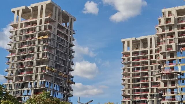 A tall modern residential building under construction against the blue sky with clouds, real estate development and architecture concept.
