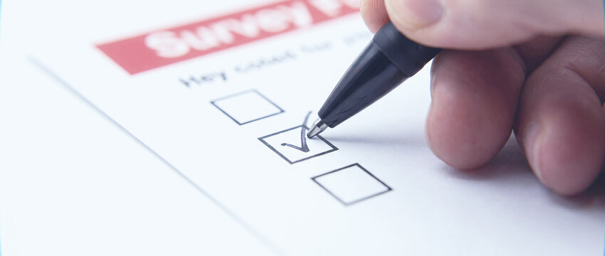 Survey questionnaire completion and feedback review documented with a pen checking boxes on paper form