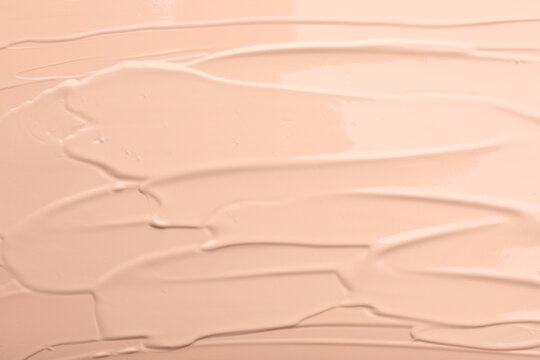 Swatches of liquid foundation as background, top view