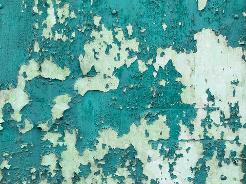 Peeling turquoise paint on an old weathered wall. 