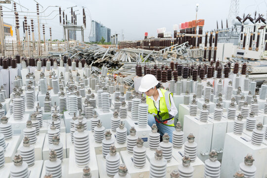 Capacitor inspection at a substation storage yard shows a technician kneeling with a tablet beside rows of capacitor units.