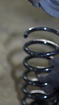 Mechanic installs a rubber spring isolator pad on coil spring.