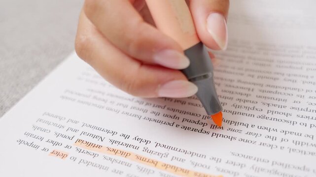 Female student highlighting text in a book with orange marker
