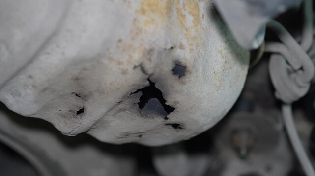 Close-up of a severe rust hole corrosion in car underbody metal.