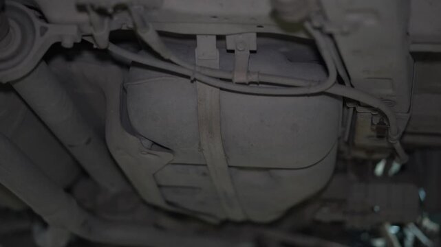 View of a plastic car fuel tank with mounting straps underneath.