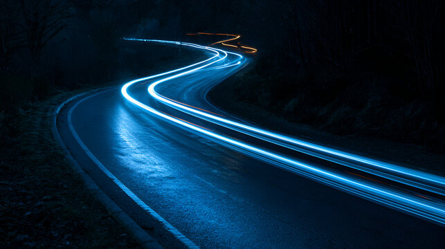 Long exposure photograph of bright blue light trails on a dark, wet, winding road at night.