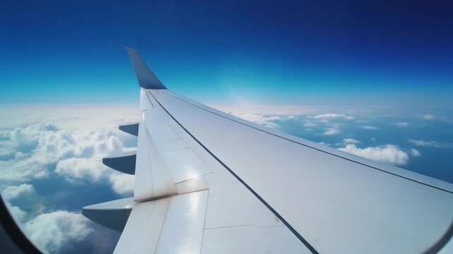 旅客機の白い翼が深い青空と柔らかな雲海の上を伸び高高度の静けさと旅情を感じさせる