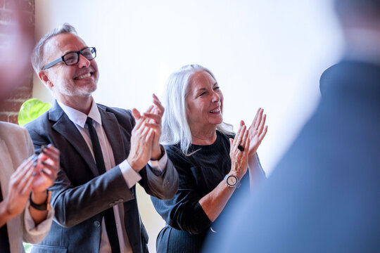 Smiling older white man and woman applauding at a professional event