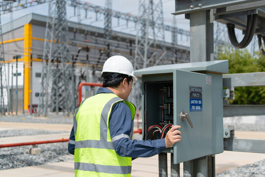 In this substation, inspection of a control cabinet is performed by a technician wearing a hard hat checking the wiring.