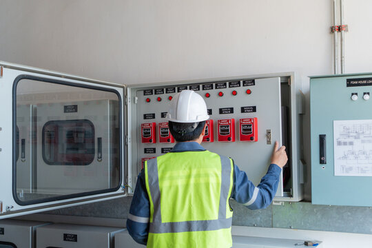 Fire protection system's fire alarm control panel is inspected by a technician inside a building beside its open cabinet door.