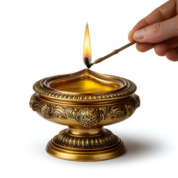 Hand lighting a decorative brass diya lamp with a small stick