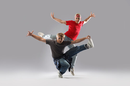 Two men dancing hip-hop on light grey background