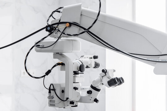 Close view of suspended ophthalmic surgical microscope with binocular eyepieces, modern equipment for eye surgery and cataract treatment.