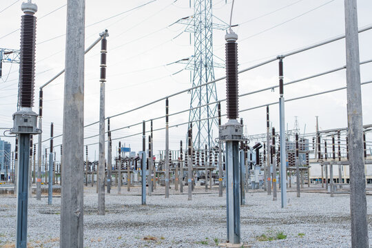 Substation patrol inspection view of an outdoor high voltage switchyard with a disconnect switch, post insulators and a lattice tower.