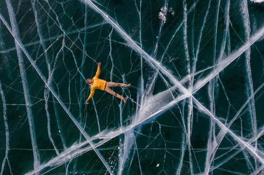 Man Lying on the Deep Blue Cracked Ice of Frozen Lake Baikal