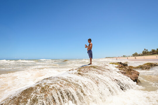 Fisherman standing on reef as tide rushes over stones