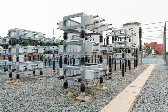 Capacitor bank inspection at an outdoor substation shows stacked capacitor units on steel frames, insulators, wiring, and the disconnect switch.