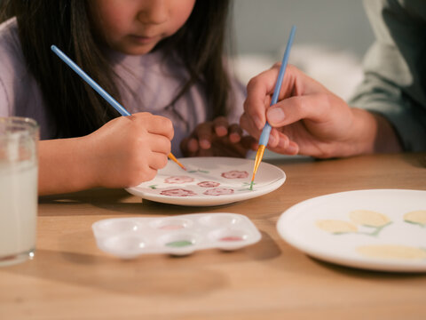 Child Paints Flowers on a Plate With Help From Mom