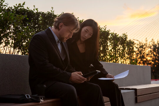 Business colleagues reviewing contract outdoors at sunset