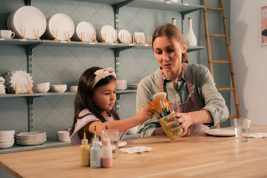 Mother giving paintbrushes to her daughter