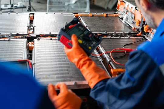Routine electric vehicle battery testing uses an insulation tester over an open EV battery pack in a repair workshop.