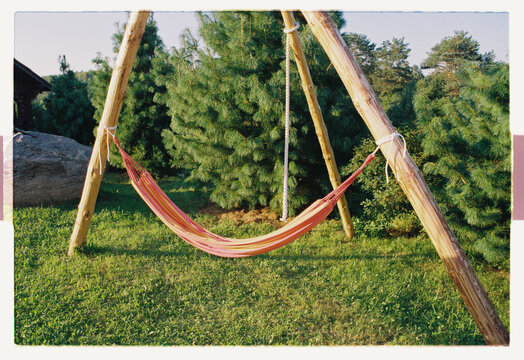 A striped hammock sways empty on a warm summer afternoon