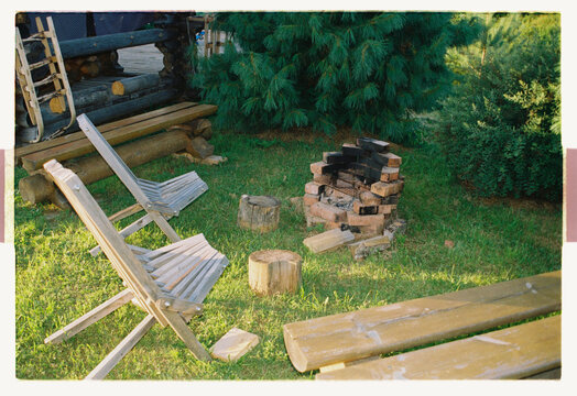 A folding chair beside a brick fire pit at a log cabin
