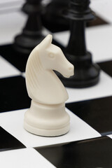 White chess knight on black and white board © Anastasiia