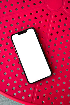 Mobile Phone with Blank White Screen on a Red Textured Background.