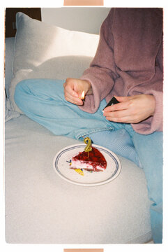Mother lighting a number two birthday candle on a slice of cake