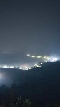 Vertical video - Timelapse of a rural town blanketed by the fog at night