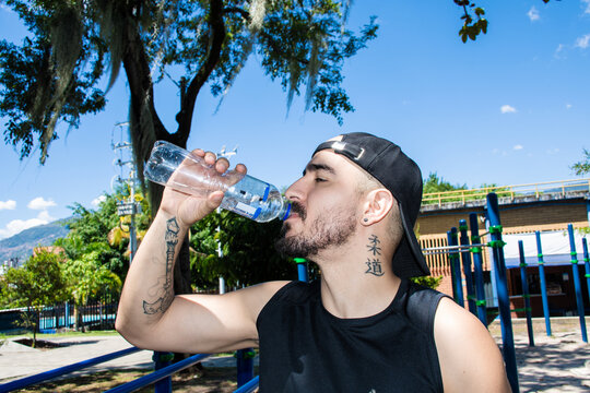 Man Drinks Water at a Park During the Day