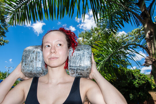 Woman Carries Large Weights on Her Shoulders Under Blue Sky