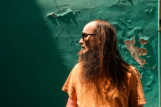 Bearded Man Standing Against a Textured Green Wall