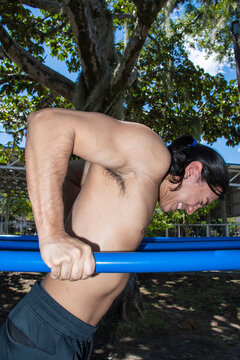 Man Performs Exercise Under a Tree in an Outdoor Gym