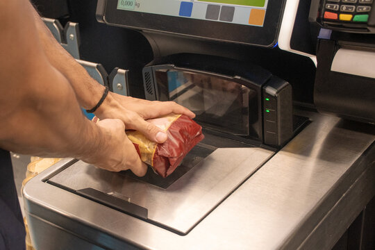 Person Weighing a Package at a Self-Service Checkout Station