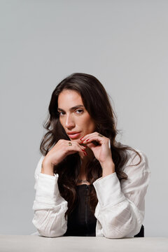 Model Poses With Hands Under Chin in Studio Setting