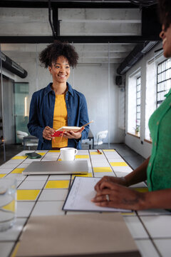 Smiling Woman Leading Informal Office Meeting With Notebook