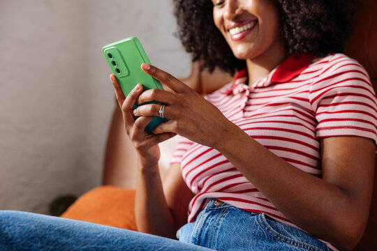 Smiling Woman Texting on Green Smartphone at Home