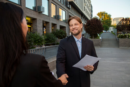 Two colleagues discussing contract outdoors in urban setting