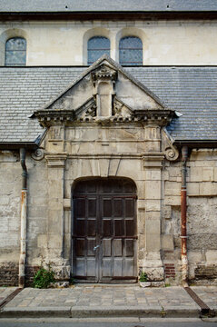 An ancient wooden door on a French stone building facade