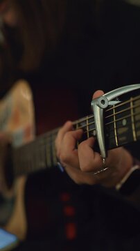 Close up of musician playing acoustic guitar with capo and ring on finger
