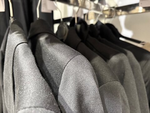 Close up of black jackets and dark clothing hanging on rack in fashion retail store, elegant monochrome apparel collection