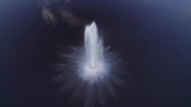 Drone flying over a fountain on the lake in Valga, Estonia at dusk