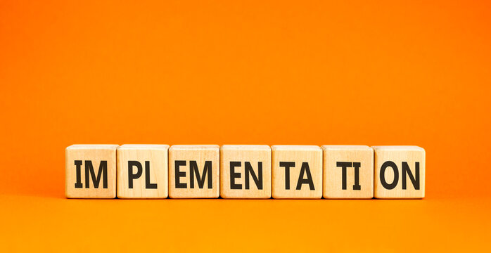 Implementation word symbol. Concept word Implementation on beautiful wooden blocks. Beautiful orange table orange background. Business implementation word concept. Copy space.