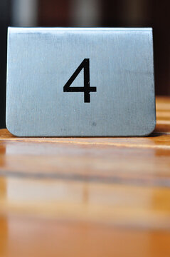 Brushed metal table number 4 on a wooden dining table