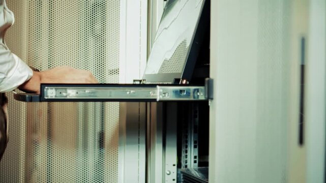 Engineer Opening Console Drawer Monitor In Server Rack Cabinet. Data Center Mainframe Hardware Maintenance. System Administration 