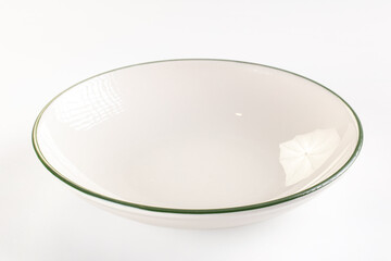 Empty ceramic bowl with green rim on white background, glossy surface reflecting light, minimal...